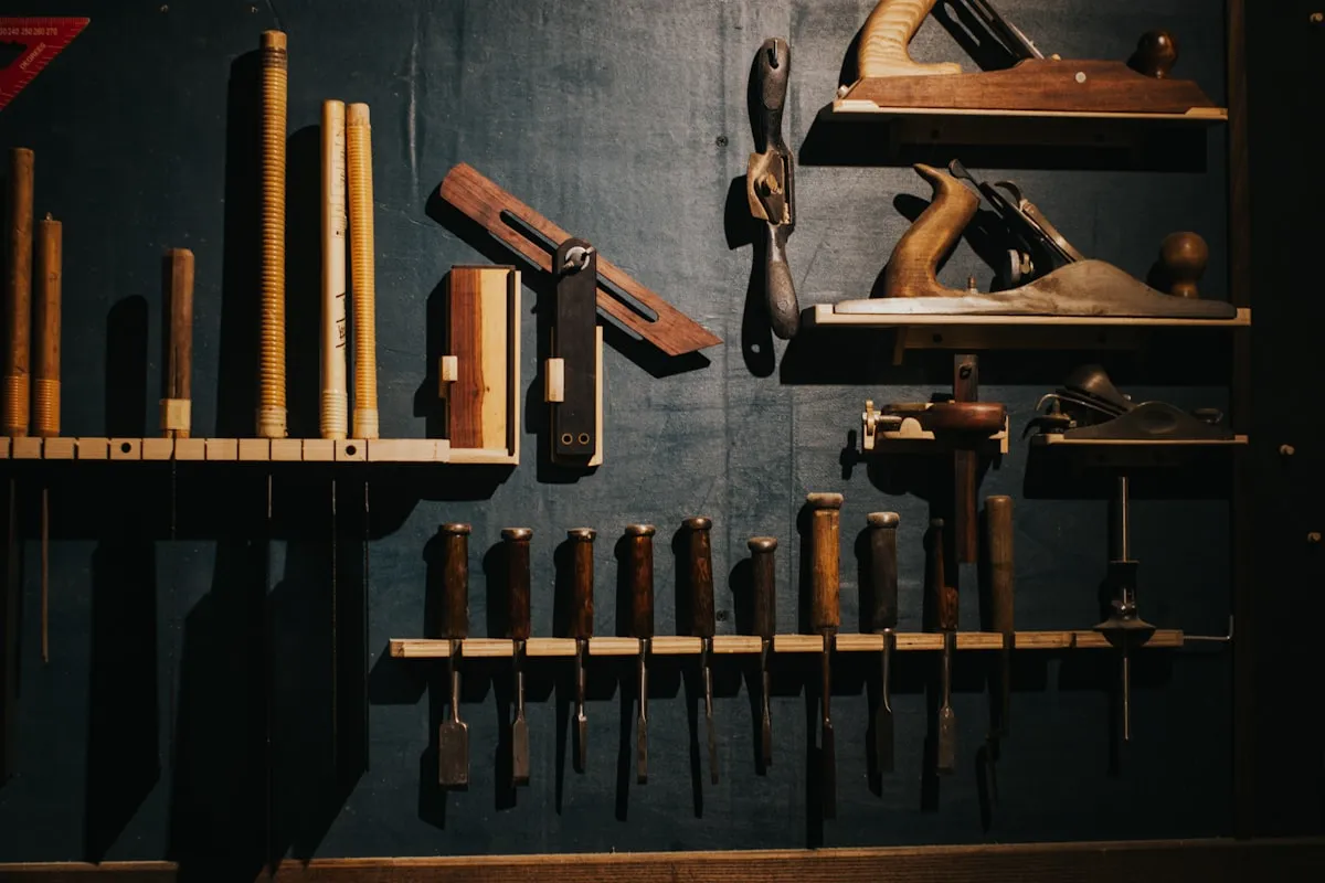 Traditional woodworking hand tools neatly organized on a dark workshop wall, representing precision craftsmanship.